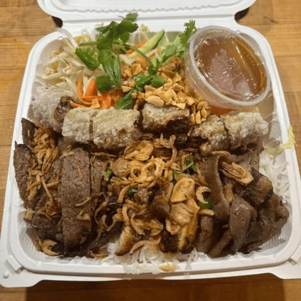 Pho Saigon Basil's Vietnamese dish with beef, spring rolls, vegetables, and sauce in a takeout container.