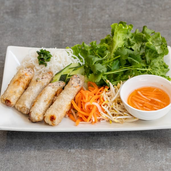 Vietnamese fried spring rolls with vermicelli noodles, fresh herbs, pickled vegetables, and dipping sauce.