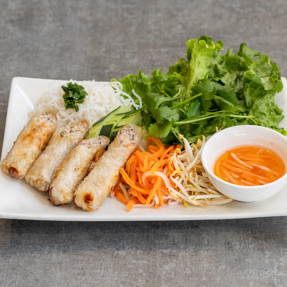 Vietnamese fried spring rolls with vermicelli noodles, fresh herbs, pickled vegetables, and dipping sauce.