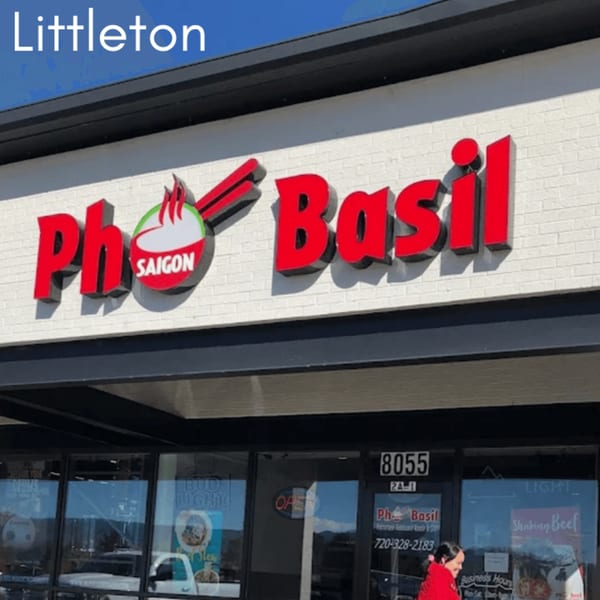 The exterior of Pho Saigon Basil restaurant, featuring its red and white sign against a brick wall.