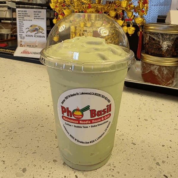 A large Pho Saigon Basil boba smoothie with a domed lid sits on a speckled counter.