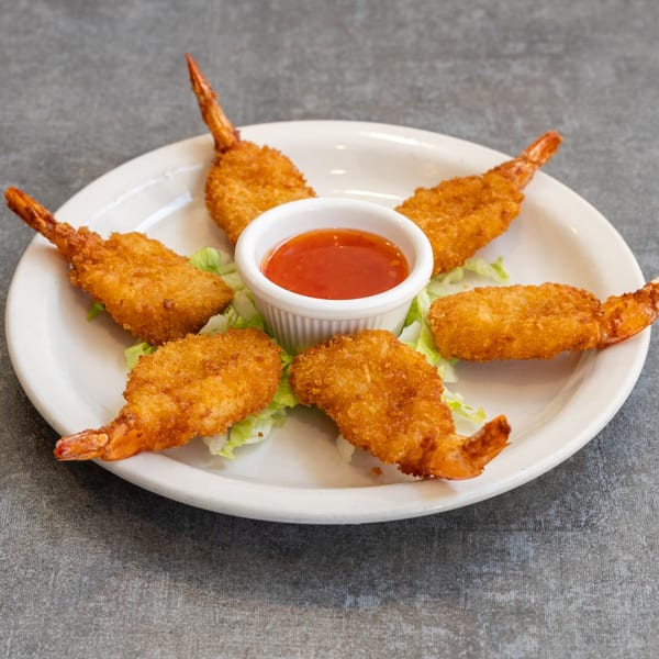 Six crispy fried shrimp with tails on, arranged around a small bowl of sweet chili sauce on a white plate.