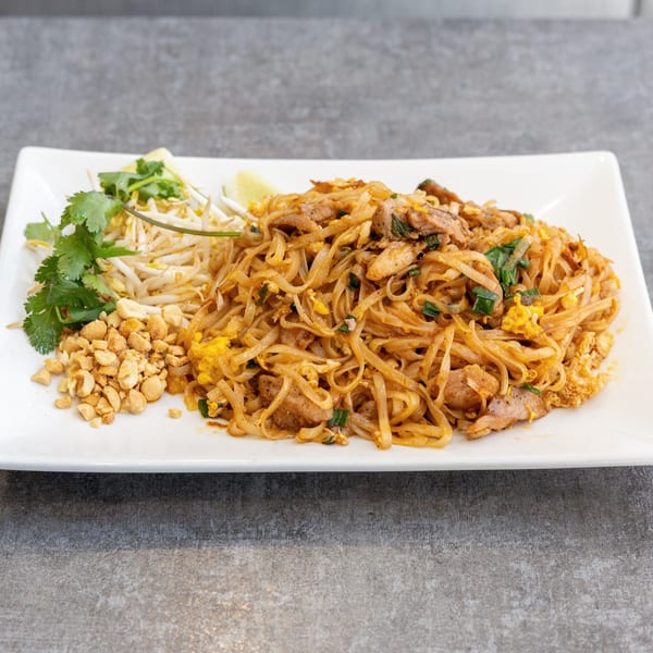 A plate of Vietnamese Pad Thai with chicken, peanuts, bean sprouts, cilantro, and lime.