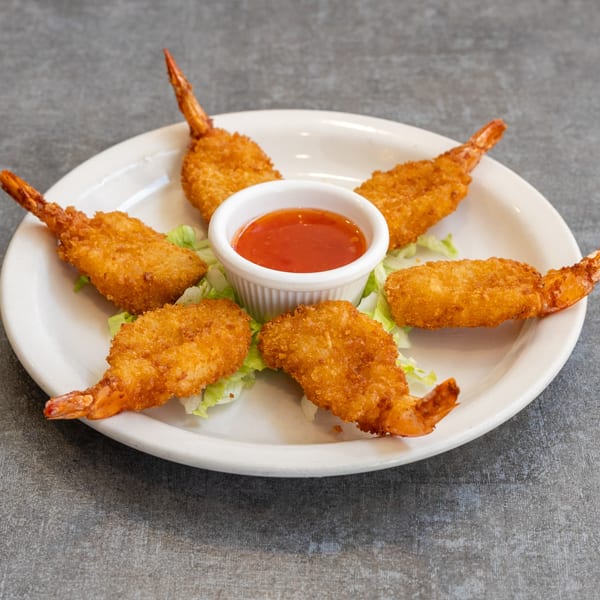 Six crispy fried shrimp with tails on, arranged around a small bowl of sweet chili sauce on a white plate.