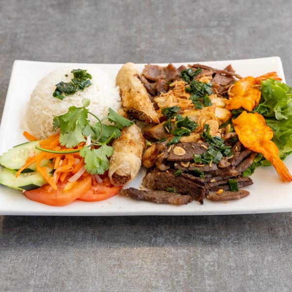 Vietnamese platter with rice, spring rolls, grilled beef, shrimp, and fresh vegetables.