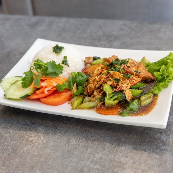 Vietnamese stir-fry with chicken, broccoli, carrots, and fried onions, served with rice and salad.